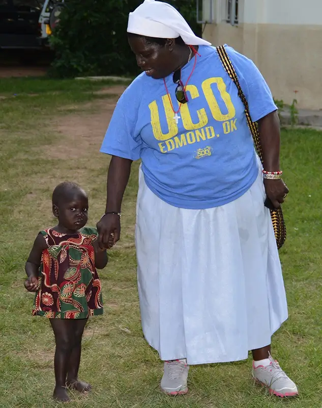 Sister Rosemary holding child's hand